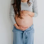 Schwangere Frau umfasst nackten Bauch und fragt sich ob eine Schwangerschaftsmassage erlaubt ist